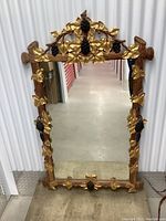 Front view of entire mirror showing carved wooden frame with gold leaf grape leaves and dark grape clusters