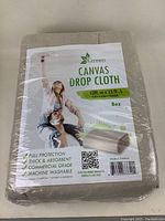 Packaged canvas drop cloth with branding and size label visible.