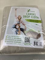 Photo of one green lifestyle canvas drop cloth package showing 12ft x 15ft, 8oz specifications and features.