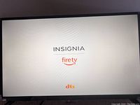 Front view of the TV powered on showing the Insignia Fire TV logo on screen with DTS branding.