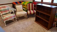 Three vintage French style chairs and wooden bookcase shown together in room