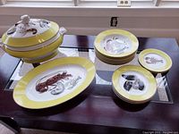 Front view of the complete set showing soup tureen with lid, serving platter, bowls, and plates arranged on table