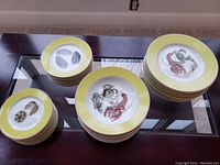 Four stacks of dishes showing small plates, bowls and large dinner plates on a table