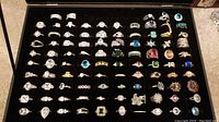 Top view of black velvet tray holding approximately 75 assorted costume jewelry rings