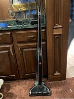 Full view of black and silver Hoover Linx cordless stick vacuum cleaner, standing upright showing slim design and logo on body.