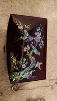 Top view of rectangular wood jewelry box with bird and floral mother-of-pearl inlay decoration on lid