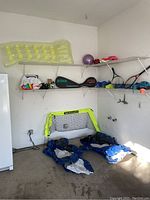 Overview of garage corner showing all sports items including inflatables, tennis rackets, soccer goal, and exercise ball.