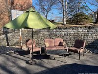 Full view of outdoor patio furniture including two armchairs, loveseat, coffee table, and shade umbrella.