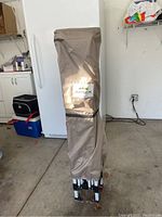 Standing view of the canopy in beige cover with metal frame bottom and Apex logo