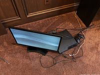 Overview of PS3 slim console, controller, LG monitor and cables on carpet