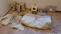 Queen size comforter and pillows laid out on carpet