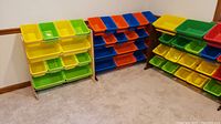 Three storage racks each with 18 colorful plastic bins in yellow, green, blue, and orange, arranged in rows on wooden frames