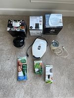 Photo of the lot showing Bianca fondue set box, Big Boss multi blender box, Cuizen rice cooker box, Silex waffle maker on the floor, and Food Saver vacuum system bags and unit parts.