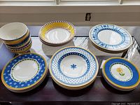 Overview of multiple plates and bowls from Villeroy & Boch Twist Anna collection arranged on a dark surface under window light.