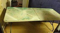 View of the plastic folding table fully extended showing paint stains and fold line.