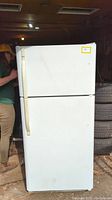 Closed view of white Kenmore refrigerator with top freezer compartment and bottom fridge compartment, showing textured white exterior with vertical handle on the left side.