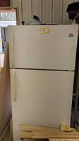 Full frontal view of white refrigerator with top freezer and bottom fridge doors. Yellow sticker with number 45 on top door.
