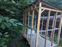 Angled side view of wooden stud frame on trailer showing floor and roof