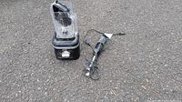 Photo shows black KitchenAid countertop blender with a clear plastic blending jar on the left and a black KitchenAid immersion blender with attached cord lying on the right on pavement.