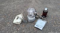 Photo showing the white hand mixer with two beaters, clear bowl food processor with metal base, black and silver electric coffee grinder, and silver digital kitchen scale on ground.