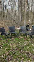 Four dark brown resin wicker chairs with metal frames lined up outdoors on grass.