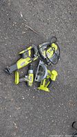 All four Ryobi power tools laid out on pavement: reciprocating saw, circular saw, jigsaw, and drill.