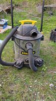 Full front view of Stanley wet dry vacuum with hose attached, showing yellow handle and black wheels.