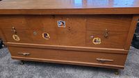 Front and side view of wooden cedar lined chest with visible wear and cartoon character stickers.