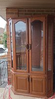 Front view of lighted china cabinet with star design on glass doors and wooden lower cupboard doors, showing some marks and overall condition.