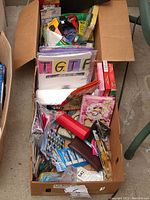 Top-down photo of a box filled with assorted office supplies, cards, albums, and cleaning pads.