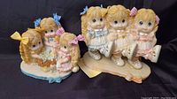 Full view of two ceramic figurines featuring girls with bows and dresses