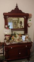 Front view of antique wooden dresser with attached mirror and carved finial
