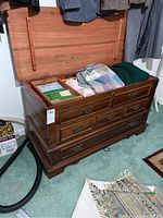 Angled view of the cedar chest showing the open lid and some clothing inside.