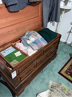 Womens sweaters folded inside a wooden chest, showing pastel and muted color tones