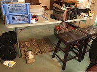 Plastic folding table set up indoors with various unrelated items placed on and under it to show context and scale.