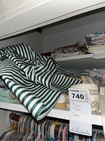 Shelf with striped pillow cases and folded linens, label showing lot number 740 and description pillow cases and doilies