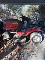Side view of red Troy-Bilt riding mower showing front and rear tires and mowing deck