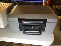 Gray Sentry 2110 safe with black handle and lock on a table