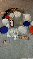 Overview of assorted ceramic baking dishes, glass bowls, round and rectangular shapes, various containers with lids and small ceramic jars.