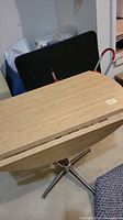 Folding wooden leaf table with silver metal base, folded edge visible