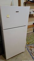 White Hotpoint top freezer refrigerator with closed doors showing full appliance.