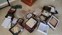 Wide shot showing the assortment of picture frames and related items arranged on carpeted floor.