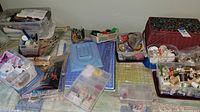 Wide view of sewing supplies including threads, pattern rulers, cutting mats, and organized boxes showing a variety of sewing tools and accessories.