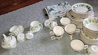 Full set of shamrock patterned plates, cups, bowls, and napkins displayed