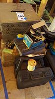Overview of the lot showing stacked tackle boxes, a vintage Penn reel in its box, fishing line spool, and other assorted fishing gear.