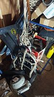 Overall view showing black folding hand truck with rope and assorted garden tools including leaf blower and boxes