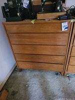 Front view of an American modern chest of drawers with five drawers showing wear and positioned beside another similar piece, taken to document condition and appearance.