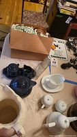 Overall view showing dark blue Fiesta ware, coasters, and white ceramic creamer and sugar on table
