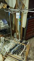 Photo of metal spider rack with arms and multiple plastic and wooden hangers surrounding the wooden quilt rack.