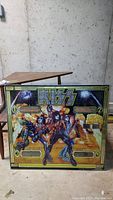 Kiss pinball backglass featuring band members in colorful costumes, yellow and black border, storing in basement with no outside access.